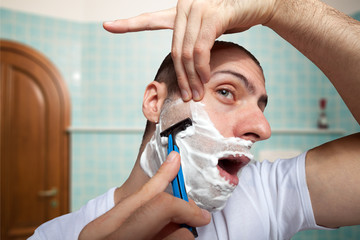 Man using a razor to shave his beard off