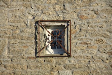 vergittertes kleines Fenster in einer Bruchstenmauerwand