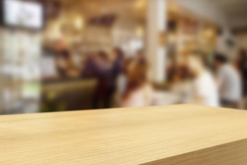 Empty wooden table and blurred people in cafe background