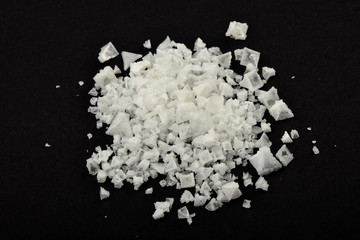 Handful of white Cyprian pyramid sea salt isolated on black