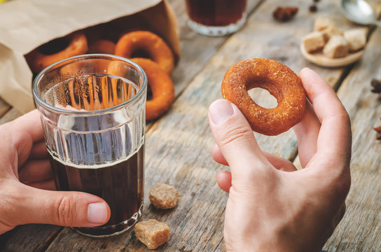 man holding glass of coffee and pumpkin donut