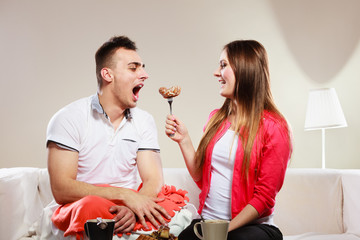Smiling woman feeding happy man with cake.