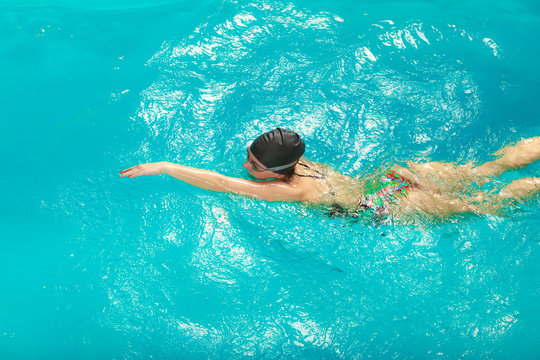 Woman athlete swimming crawl stroke in pool.