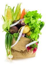 Paper bag with organic vegetables and  measuring tape on white background
