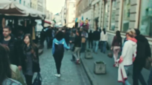 Blurred crowd of walking people in the city with buildings in