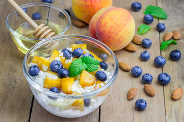Fresh cottage cheese with peach, blueberry, almonds and honey. Concept of healthy eating for breakfast.