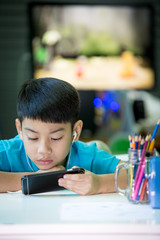 Happy asian boy usins cellphone at home