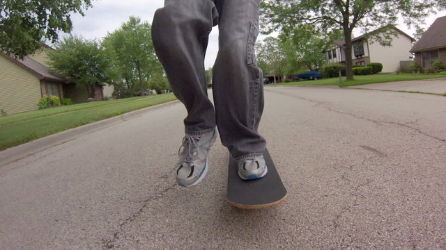 Skateboarding Close Up – Low angle tracking shot, in front of a skater skateboarding down the street.