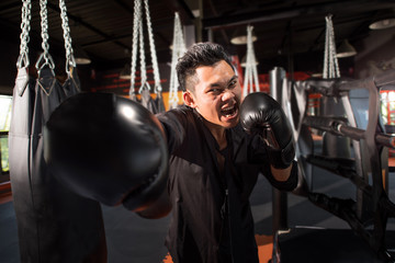 young aggressive businessman training shadow boxing at gym with gloves throwing vicious punch in...