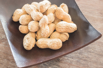 Salted peanuts on wooden bowl