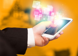 Hand holding smart phone with abstract glowing squares