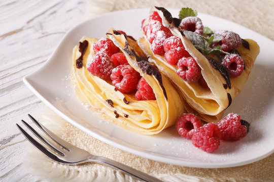 Delicious raspberry crepes close-up on a plate. Horizontal
