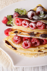 Beautiful crepes with raspberries and chocolate close-up. vertical
