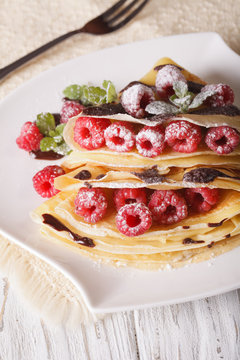 raspberry crepes with chocolate close-up on a plate. vertical