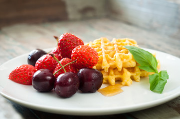 Home made waffles drizzled with maple syrup and served with fresh strawberries and blueberries.