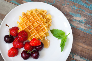 Home made waffles drizzled with maple syrup and served with fresh strawberries and blueberries.