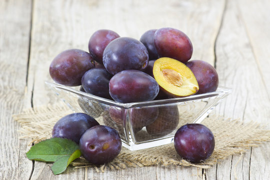 fresh plums in a bowl on old wooden background