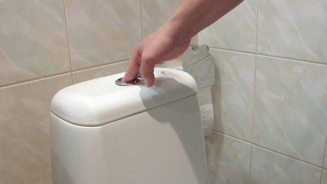 Female hand pushing button flushing toilet