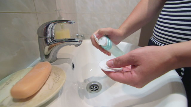 Woman applying lotion for face in the bathroom