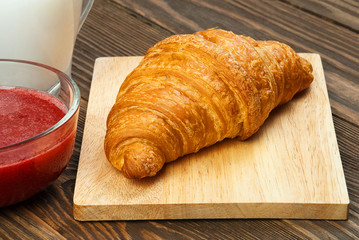 Croissant, jam and milk close up.