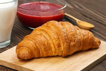 Croissant, jam and milk close up.