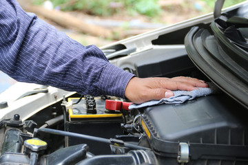 Man is cleaning his car engine with a rag.