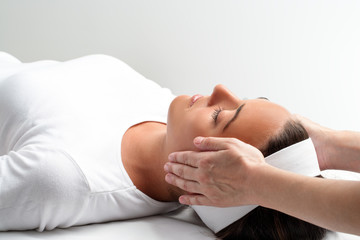 Therapist doing reiki with hands next to woman's head.