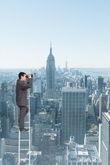 Naklejka premium Composite image of businessman standing on ladder 