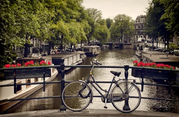 Türaufkleber Fahrrad auf der Fußgängerbrücke mit Blick auf einen Kanal in Amsterdam geparkt © Borna_Mir