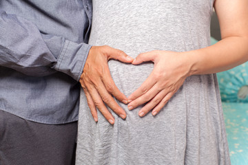 Pregnant couple with heart hands