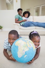 Fototapeta premium Happy siblings lying on the floor holding globe