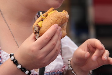 Frau im Dirndl isst Bratwursbrötchen