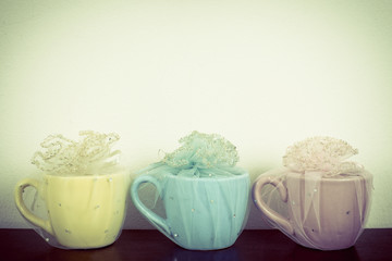 Three mug on wooden table over grunge background. Colorful stack coffee cups on wood board. Vintage retro effect style pictures.