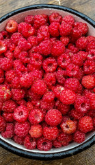 Ripe sweet raspberries in bowl on table close-up