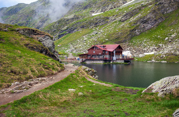 Fototapeta na wymiar Idyllic view with typical lodge on Balea Lake shore in Fagaras M