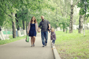 Obraz premium Mom and young daughter and dad, a young family on a walk in the park in summer