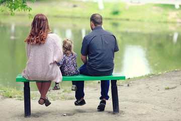 Mom and young daughter and dad, a young family on a walk in the park in summer