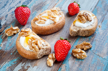 Greek barley rusks topped with Greek yogurt, honey and walnuts and served with some fresh strawberries.