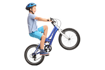 Little boy doing a wheelie on a small blue bike
