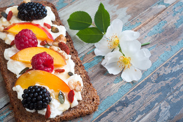 Sourdough rye bread open sandwich with ricotta,nectarine,berries,nuts and seeds with honey drizzle.