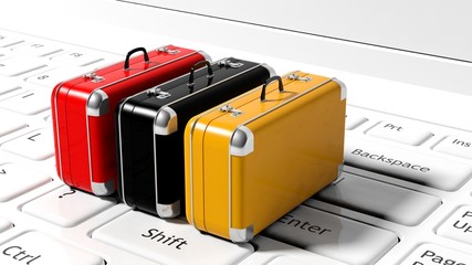 Colorful suitcases on white laptop keyboard