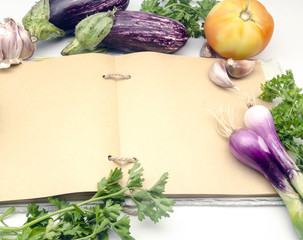 Cuaderno de recetas de cocina abierto en pagina en blanco rodeado de vegetales