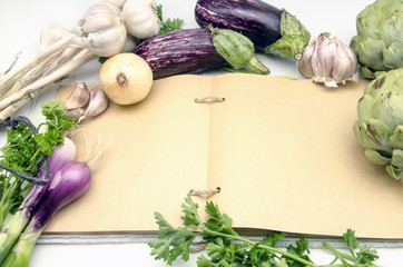 Cuaderno de recetas de cocina abierto en pagina en blanco rodeado de vegetales