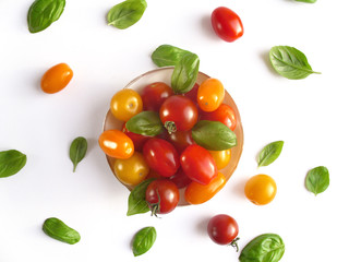 Kleine Schale mit verschiedenen Sorten Mini-Tomaten, mit Basilikum dekoriert. Draufsicht.