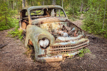 Old rusted scrap car in a forest