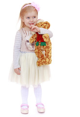 Very little blond Caucasian girl dressed in a beautiful white dr