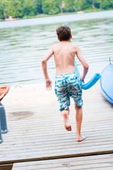 Naklejka na ściany i meble boy jumping off a dock into a lake
