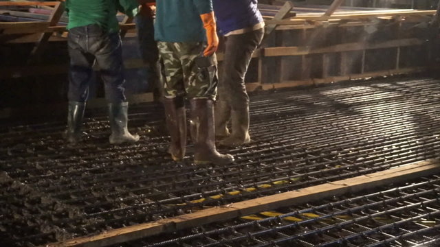 Pouring concrete mix from cement mixer on concreting formwork at night