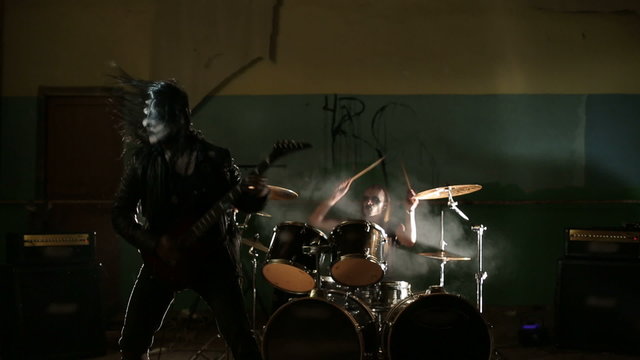 Vocalist and drummer of black metal band at dark background