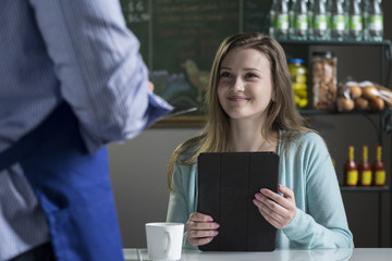 A young woman ordering food from a waiter